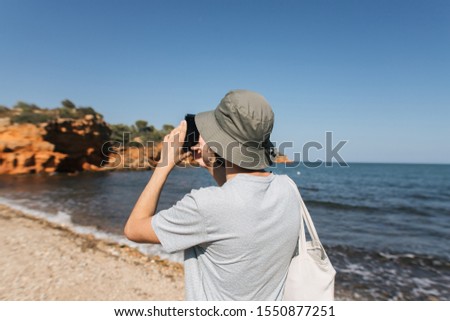 Man taking photos with his cell phone at the sea