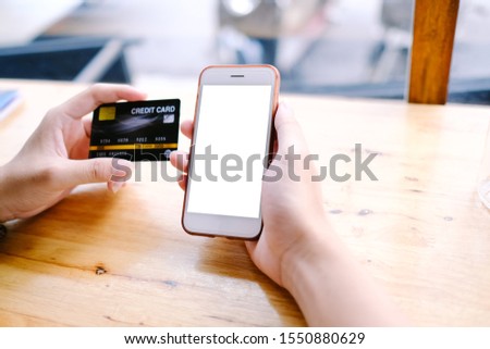 Close up of man using blank cell phone and credit card sending massages shopping online on the coffee shop.