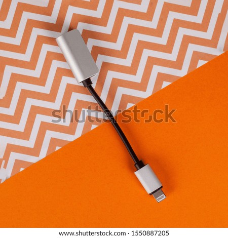 USB cable for mobile phone on colorful orange paper background.