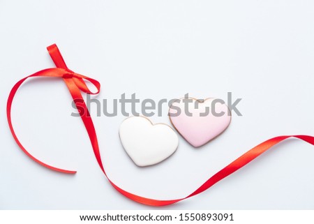 Valentine's day composition. Red sweet biscuits shaped as hearts in love with bow. Template, background. Top View. Flat lay. Copy space