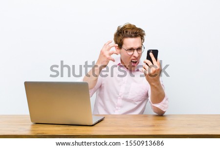 young red head businessman working in his desk with a monile phone