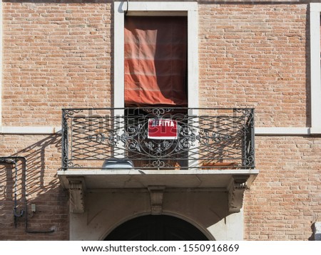 Ferrara, Italy. Elegant building for rent. On the balcony there is a rented sign. Affitta means rent.