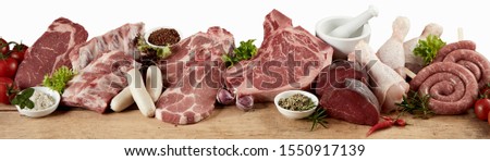 Large variety of fresh raw meat for a barbecue with beef steak, sausage, chicken, pork, spare ribs and nackensteak displayed with herbs in a panorama banner suitable for butchery advertising Royalty-Free Stock Photo #1550917139