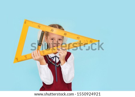 Girl in a school uniform with a ruler in her hands. Back to school concept.