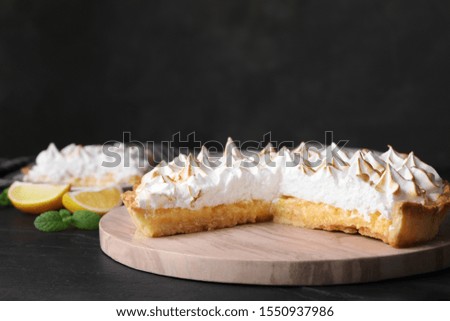 Serving board with delicious lemon meringue pie on black table