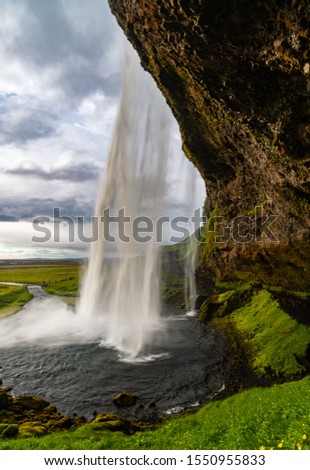 Seljalandsvoss magic waterfall is a natural wonder and a tourist attraction in South Iceland Europe with Water Curtain splashing from volcanic rock on a cloudy evening at midsummer in June