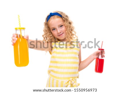 Picture of happy child with fair red curly hair drinks orange and red juices
