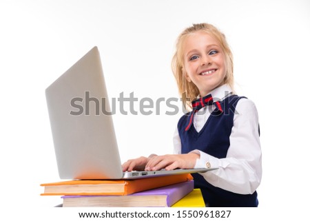 Picture of a little girl with blonde hair do homework with laptop and many books