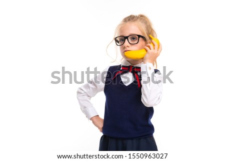 Picture of a little girl with blonde hair talking on banana