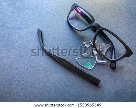 plastic glasses with a broken lens and a torn earhook on a dark background.