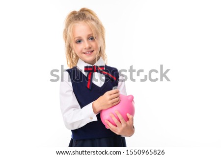 Picture of a little girl with blonde hair holds pink pig moneybox and smiles