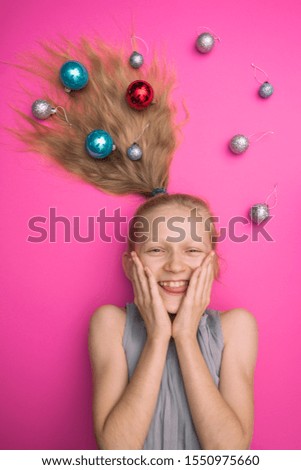 crazy happy and bright New Years holiday. girl with christmas balls on pink background
