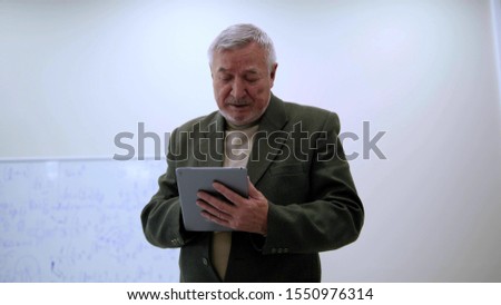 Professor in jacket work with tablet and sigh.