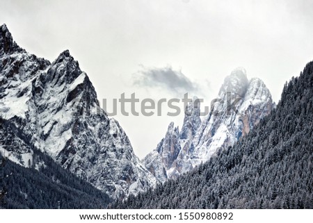 Winter in the Alps with the snow covered mountains of the Dolomites and a dramatic sky, black and white photo
