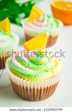 Cupcakes with orange juice and zest decorated with Swiss meringue cream on a wooden background