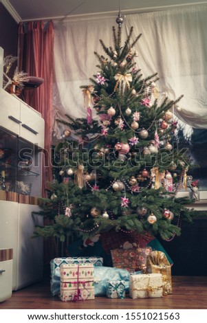 It is Holy night, the decorated Christmas tree is in the living room and below are the wrapped Christmas presents. Authentic picture of private party.