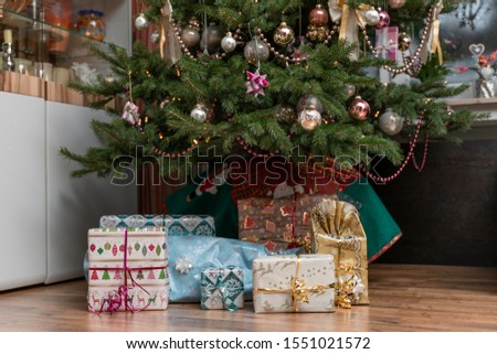 It is Holy night, the decorated Christmas tree is in the living room and below are the wrapped Christmas presents. Authentic picture of private party.