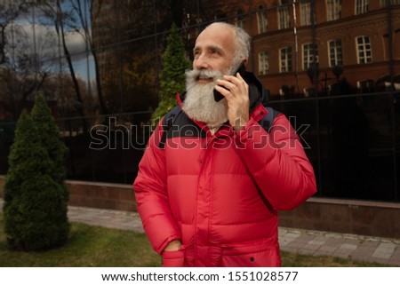 Smiling senior bearded man doing a phone call.