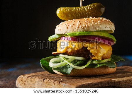 Fast food. Vegetarian burger with a chop, cucumber, tomato and lettuce. Tasty sandwich for lunch. Dark background