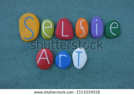 Selfie art text composed with colored stone letters over green sand