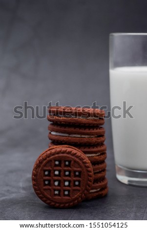 chocolate chip cookies with cream filling with milk in a glass on a marble black background