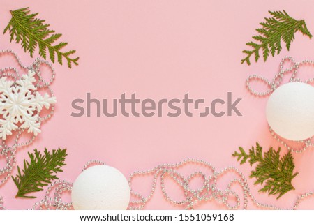 Holiday christmas background, fir branches and silver decorative beads, white snowflakes and christmas balls on pink background, flat lay, top view