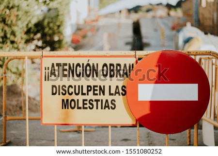Traffic sign prohibited the passage and fences of works with phrase in Spanish "Attention works, sorry for the inconvenience"