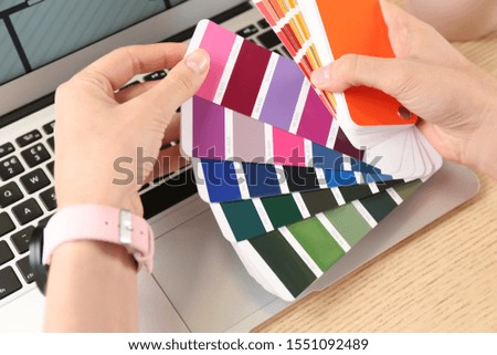 Woman with palette samples at wooden table, closeup