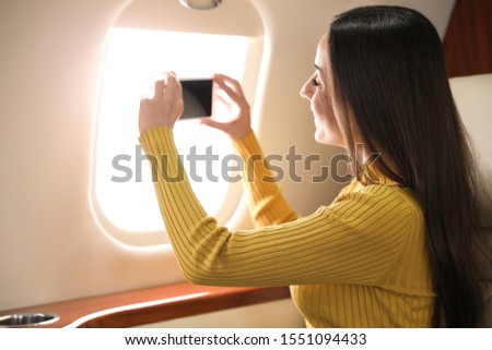 Young woman taking photo on plane. Comfortable flight