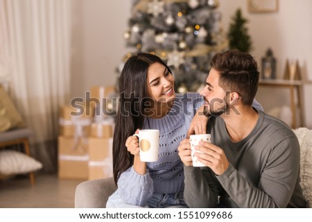 Happy couple with drinks in living room decorated for Christmas