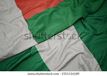 waving colorful flag of nigeria and national flag of madagascar. macro