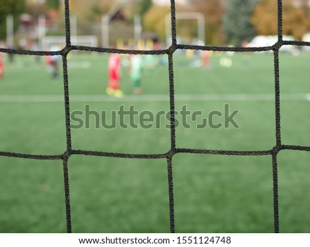 Young soccer players team on playground viewed through gate net.