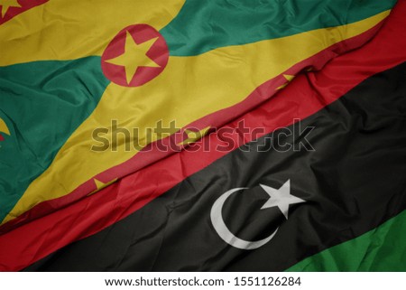 waving colorful flag of libya and national flag of grenada. macro