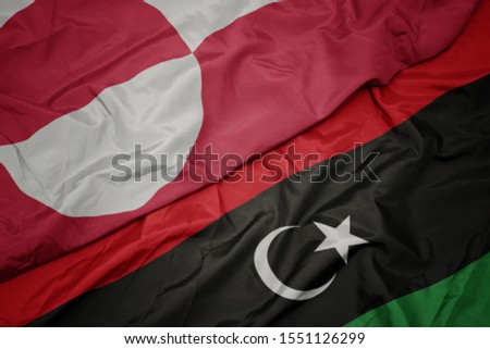 waving colorful flag of libya and national flag of greenland. macro