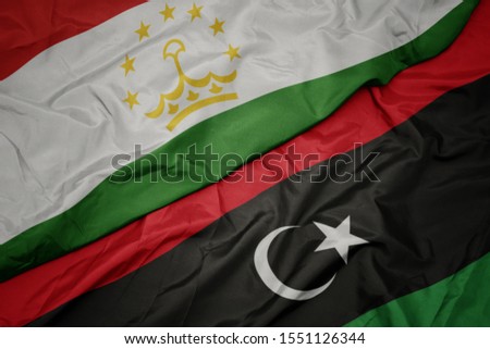 waving colorful flag of libya and national flag of tajikistan. macro