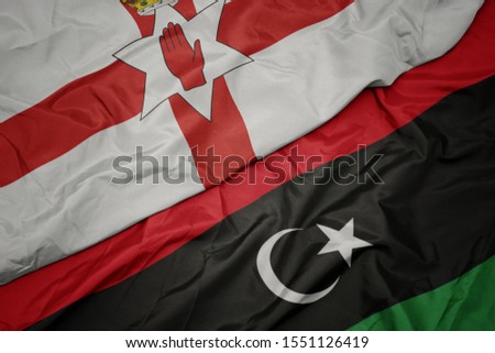 waving colorful flag of libya and national flag of northern ireland. macro