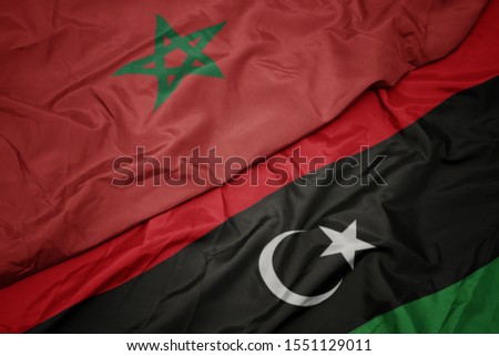 waving colorful flag of libya and national flag of morocco. macro