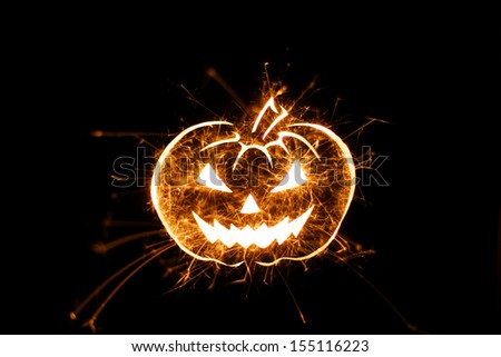 Halloween pumpkin image in fiery flying sparks on black background with copy space.