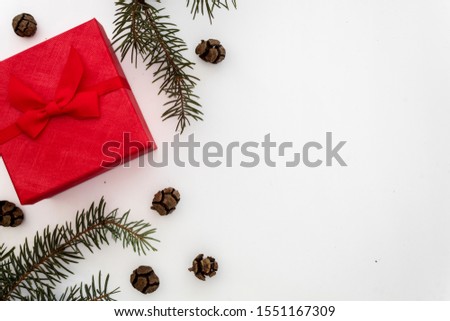 Creative Composition Useful for Christmas and New Year Greeting Card Created Using Red Gift Box, Green Pine Branches and Small Pine Cones. Copy Space on The Right Side