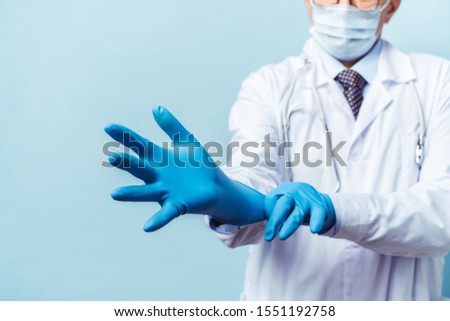 doctor puts on rubber gloves, healthcare and medicine. Isolate on blue background