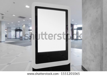 Mockup of blank white vertical indoor advertising poster stand with black frame in shopping centre or mall