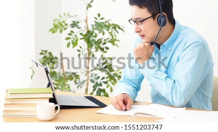 Online lesson concept. Young asian man studying in room. e-learning. Royalty-Free Stock Photo #1551203747