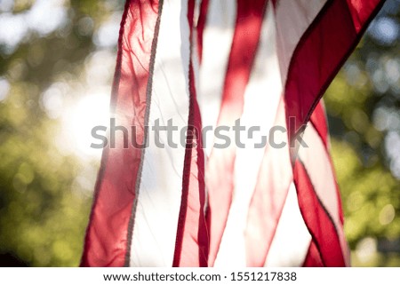 A closeup shot of the unites states flag hanging with the sun shining in the background