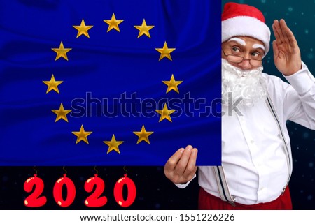 Santa Claus with a beard holds a beautiful photo of European Union flag with a festive date 2020, the concept of tourism, the new year, economic and political prospects