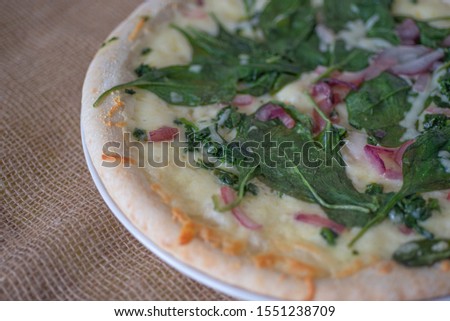 Fragment of vegeterian pizza with spinach, cheese  and onion on burlap surface. 