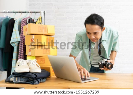 Asian man working laptop computer With hold the camera selling online