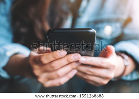 Closeup image of a woman holding , using and looking at mobile phone