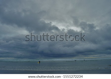 The minimalist picture of surfers in beautiful and serene Long Beach, Tofino of Vancouver Islands, Canada during a windy and very cloudy day.