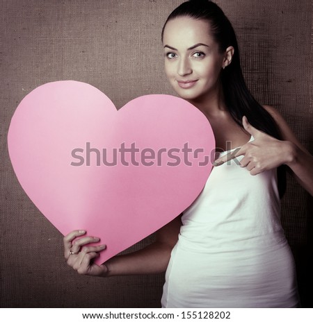 portrait of attractive smiling young woman with pink heart, love holiday valentine symbol over canvas background, toned