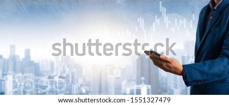 Businessman using smart phone with finance and banking profit graph of stock market trade indicator financial with city background